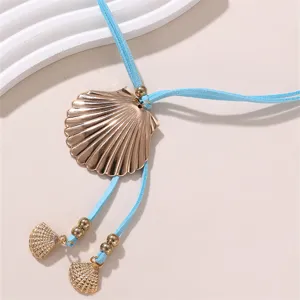 Detailaufnahme einer modischen blauen Wildleder-Halskette mit goldfarbenem Muschel-Anhänger.