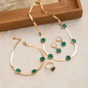 Detailansicht des vergoldeten Schmucksets mit grünen Kleeblattmotiven und Schlangenkette.