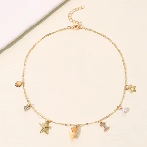 Detailansicht der goldenen Mehrfach-Anhaenger Ozean Halskette mit Muscheln und Buchstaben.