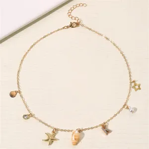 Detailaufnahme der goldenen Charm-Halskette mit Muschel und Buchstabenanhänger, tolles Design.