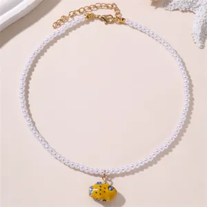 Nahaufnahme einer eleganten Perlenkette mit einem süßen gelben Fisch-Anhänger und goldenem Verschluss.