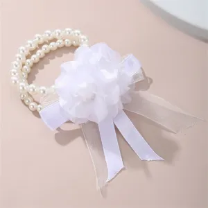 Nahaufnahme der filigranen weißen Stoffblume und des doppelten Perlenarmbands.