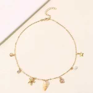 Nahaufnahme Details der goldenen Strand Ozean Charm Halskette mit Muschel Stern und Buchstaben.
