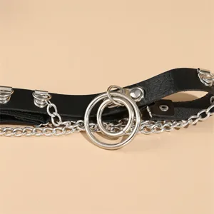 Close-up detail van zwarte leer beenketting in punkstijl met metalen ringen en kettingen.