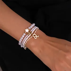 Nahaufnahme eines mehrschichtigen Perlenarmbands mit goldenem Sternzeichenanhänger.