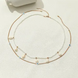Dettaglio in primo piano della catena corpo multistrato boho con perle e conchiglie.