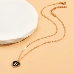 Goldfarbene Kette mit schwarzem Emaile-Herzanhänger und filigranem Buchstaben B Detail.