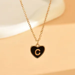 Nahaufnahme der goldenen Kette mit schwarzem Emaile-Herzanhänger und dem Buchstaben C.