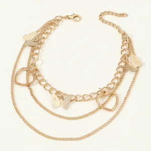 Close-up detail of the multi-layer gold-plated butterfly and heart charm anklet design.