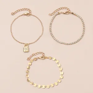 Conjunto de tobilleras doradas con candado de corazón, pedrería y discos metálicos chic.