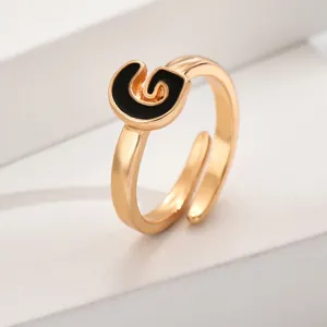 Verstellbarer goldener Buchstabenring mit schwarzem Emaille-Akzent, minimalistischer Schmuck.