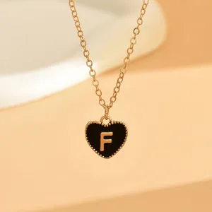 Detailaufnahme der goldenen Kette mit einem schwarzen Herzanhänger und dem Buchstaben F.
