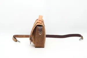 Side view detail of vintage genuine leather tooling messenger shoulder bag for women.