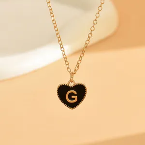 Nahaufnahme Detail der filigranen Goldkette mit schwarzem Emaile-Herz-Anhänger und Buchstabe G.