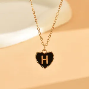Vergoldete Halskette mit schwarzem Emaile-Herz-Anhänger und edlem Buchstaben H im Detail.