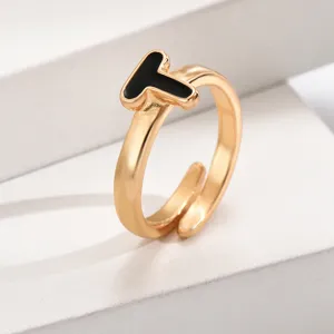 Detailaufnahme des goldenen verstellbaren offenen Damenrings mit eleganten schwarzen Buchstaben T.