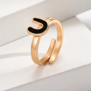 Nahaufnahme des verstellbaren goldenen Buchstaben-U-Rings mit schicker schwarzer Emaillierung.