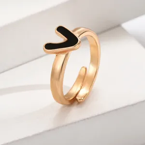 Nahaufnahme eines schicken verstellbaren vergoldeten Buchstaben-V-Rings mit schwarzem Emaile-Inlay.