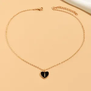 Goldfarbene Kette mit schwarzem Herzanhänger und Buchstabe I, eleganter Modeschmuck.
