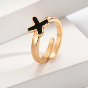 Nahaufnahme Detail eines stilvollen goldenen offenen Rings mit einem schwarzen Kreuzmotiv.