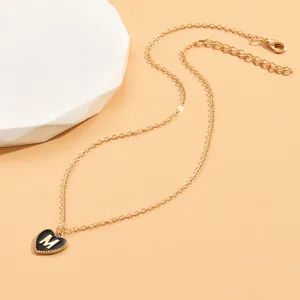 Nahaufnahme der eleganten Goldkette mit einem schwarzen herzförmigen Anhänger und Buchstabe M.
