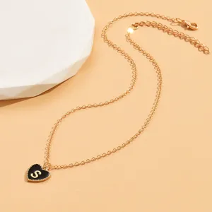 Nahaufnahme der goldenen Kette mit schwarzem Herz und Buchstaben S Anhänger, feines Detail.