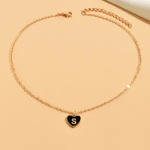 Nahaufnahme der goldfarbenen Halskette mit schwarzem Emaile-Herz-Anhänger und Buchstaben S.