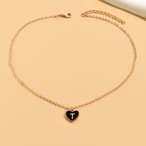 Goldfarbene Kette mit Detailaufnahme eines schwarzen Emaille Herzanhängers mit Buchstabe T.