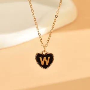 Nahaufnahme einer zarten Goldkette mit einem schwarz emaillierten Herzanhänger und Buchstabe W.