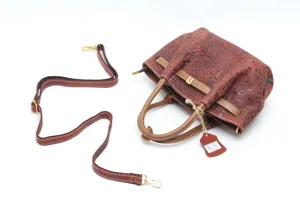 Genuine leather retro embossed dumpling handbag with shoulder strap and hang tag details.