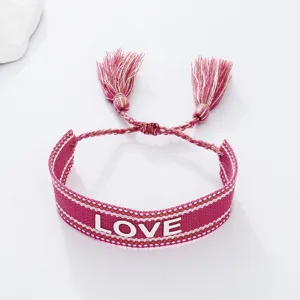 Pink woven bracelet with tassel and LOVE letter detail, stylish couple jewelry accessory.