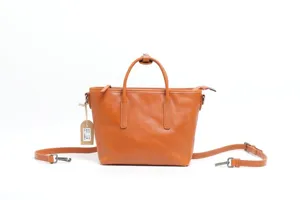 Detailed view of genuine leather tote bag, tan color with dual handles and metal hardware.