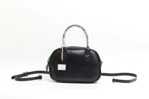 Black leather handbag detail shot showing texture, strap and attached product tag.