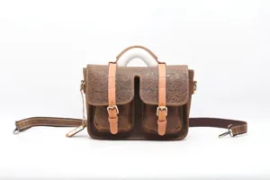 Detailed view of vintage embossed leather messenger bag, tooling flower pattern, metal hardware