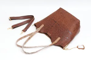 Detailed view of the brown embossed leather tote bag, showing the intricate floral pattern, sturdy handles, and adjustable shoulder strap for daily use.