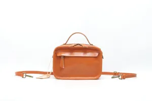 Detail of orange leather handbag, top handle, detachable crossbody strap, vintage style.