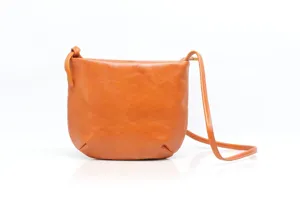 Leather crossbody bag detail showing minimalist design, smooth texture, and compact shape.