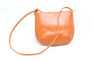Orange leather crossbody bag detail, vintage minimalist shoulder bag with fine strap.
