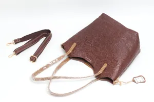 Brown embossed leather tote bag detail showing intricate vintage floral pattern texture and hardware.