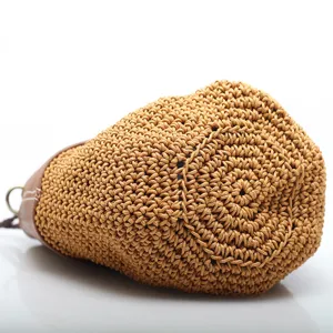 Handmade woven bucket bag with leather trim, stylish straw crossbody shoulder bag for women.