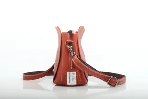 Detailed side view of the orange leather bucket handbag showcasing fine stitching and design.