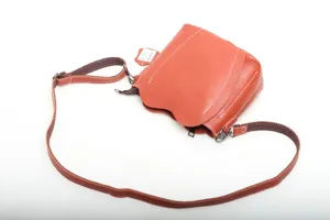 Detail view of orange leather heart crossbody bag, textured leather and metal hardware.