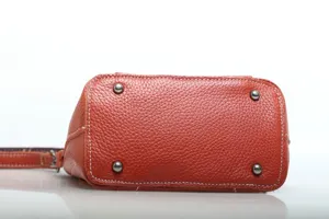 Genuine leather women crossbody bag bottom detail, orange pebbled cowhide with metal feet.