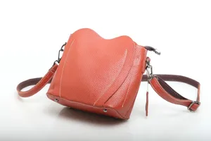 Genuine leather crossbody bag detail, orange heart flap design with white stitching.