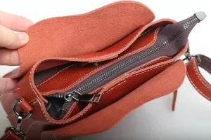 Close-up view of genuine leather shoulder bag interior compartment and metal zipper details.