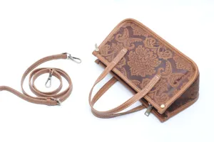 Gros plan détaillé du sac à main en cuir gaufré vintage avec motif floral et sangle amovible.