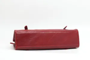 Detailed view of red genuine leather women handbag, bottom structure with metal feet and classic design.