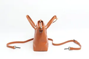 Genuine leather women handbag side view, brown cowhide shoulder crossbody commuter bag detail.