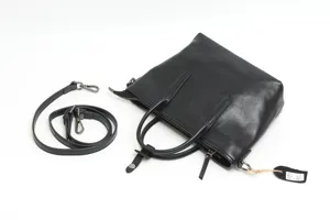 Detail view of black genuine leather handbag with zipper, sturdy handles and hardware.