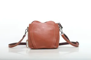 Detail shot of brown leather bag showing heart-shaped pocket, stitching and hardware.